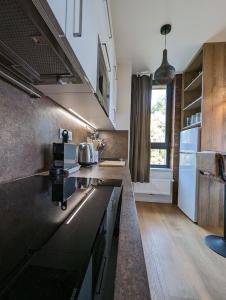 a kitchen with black counter tops and a large window at Zadov - Apartmán Srdce Šumavy in Stachy