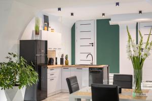 kuchnia z białymi szafkami i czarną lodówką w obiekcie Apartament w Rynku II, MyWeek w mieście Radków