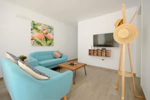 un salon avec un canapé bleu et une télévision dans l'établissement White Volcano pool, gym and activities in Sport Center Fariones included, à Puerto del Carmen