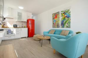un salon avec un canapé bleu et une cuisine dans l'établissement Red Volcano- pool, gym and activities in Sport Center Fariones included, à Puerto del Carmen