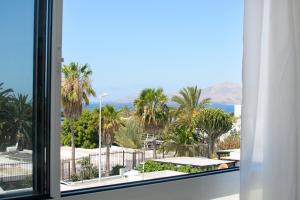 d'une fenêtre avec vue sur les palmiers et l'océan. dans l'établissement Red Volcano- pool, gym and activities in Sport Center Fariones included, à Puerto del Carmen