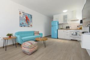 un salon avec un canapé bleu et une cuisine dans l'établissement Blue Volcano-pool, gym and activities in Sport Center Fariones included, à Puerto del Carmen
