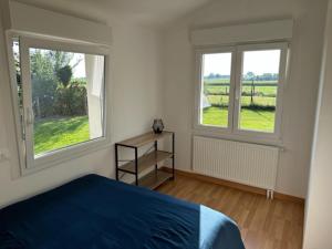 um quarto com uma cama azul e 2 janelas em Le Nid Du Moulin em Batzendorf