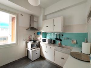 una cocina con armarios blancos y una ventana en 生活超便利的小公寓, en Atenas