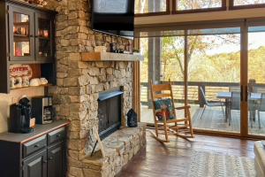 a stone fireplace in a living room with a table and chairs at Grizzly Cabin in McCaysville