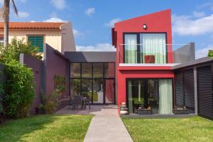 a red house with a lawn in front of it at Casas da Ribeira - Porto Bay Villa in Porto Formoso