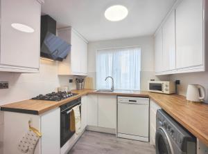 a kitchen with white cabinets and a washer and dryer at Regent House - Modern Holiday Home 10 Minutes to Manchester City Centre With Free Parking in Manchester