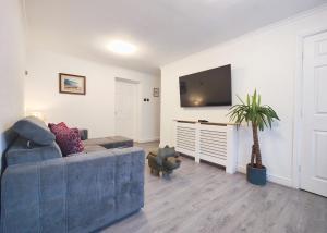 a living room with a blue couch and a tv at Regent House - Modern Holiday Home 10 Minutes to Manchester City Centre With Free Parking in Manchester