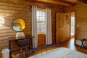 1 dormitorio en una cabaña de madera con cama y espejo en Modern Log Cabin with Vineyard Views en Penn Yan