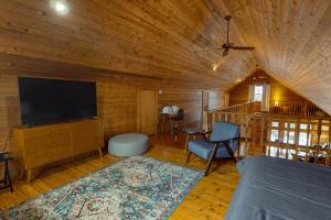 Sala de estar con cama y TV en una cabaña en Modern Log Cabin with Vineyard Views, en Penn Yan