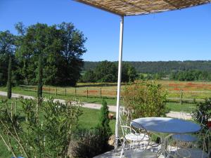 a table and chairs on a patio with a view of a field at Le Mas de Bel Air in Pierrerue