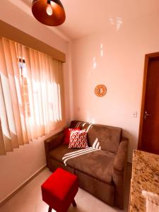 サン・トメー・ダス・レトラスにあるKitnet STL. Centroのソファと壁掛け時計のあるリビングルーム +1枚の写真