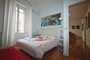 ローマにあるHouse and the City - Colosseum Apartmentsのベッドルーム1室(ベッド1台付)が備わります。壁には絵画が飾られています。