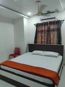 a bedroom with a bed and a red chair at Veda Residency in Machilīpatnam