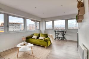 a living room with a green couch and a table at BD MINIMES - Parking Free - Proche gare - Vue in Toulouse