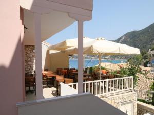 a patio with an umbrella and tables and chairs at Ionis Hotel in Agios Nikitas +16 photos