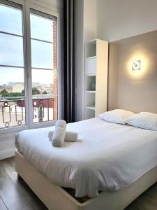 a bedroom with a white bed with a large window at FAC 4 - Tram au pied l'immeuble- Parking free in Toulouse
