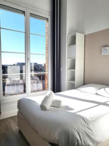 ein Schlafzimmer mit einem weißen Bett und einem großen Fenster in der Unterkunft FAC 4 - Tram au pied l'immeuble- Parking free in Toulouse