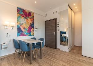 ein Esszimmer mit Tisch und Stühlen und einem Gemälde in der Unterkunft Levada Apartment - Hellenic Apartments Avlona in Avlón