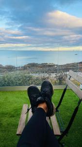 a person sitting on a bench looking out at the ocean at Luxury beach front rooms- PMA in Kirkcaldy