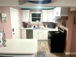 a small kitchen with white cabinets and black appliances at Beachy Paradise in Clearwater Beach +5 photos