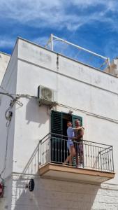 2 persone in piedi su un balcone di un edificio di Il Terrazzino del Mare a Polignano a Mare