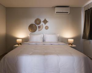 a bedroom with a large white bed with two lamps at Villa Cordel in Fernando de Noronha