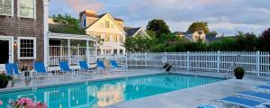 a swimming pool with blue chairs and a white fence at Chatham Wayside Inn in Chatham