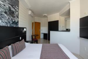 a hotel room with a bed and a kitchen at Faro Hotel Taubaté in Taubaté