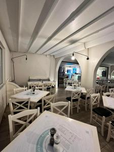 a restaurant with white tables and white chairs at Castro Hotel in Amoudara Herakliou