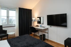 フディクスバルにあるQuality Hotel Stattのベッド、デスク、テレビが備わるホテルルームです。