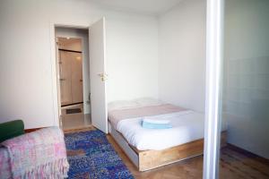 ein kleines Schlafzimmer mit einem Bett und einem Stuhl in der Unterkunft Freshly reno'd flat in between Lisbon and Sintra in Amadora