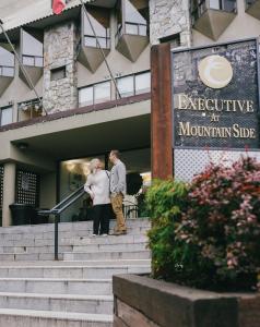a man and woman standing on steps outside of a building at Mountain Side Hotel Whistler by Executive in Whistler