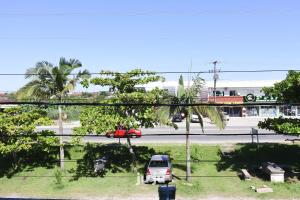 a car is parked on a street with palm trees at Pousada Ju&Ju à 400 mts DA PRAIA in Pontal do Paraná