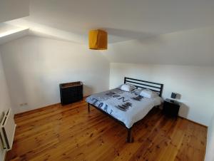 a bedroom with a bed and a wooden floor at Cosy Triplex 3 chambres in Pont-de-lʼArche