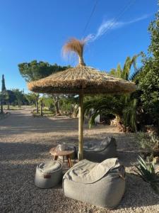 a large straw umbrella with two chairs and a table at Kleine Finca mit privatem Pool und Klima, ruhige Lage in Algaida