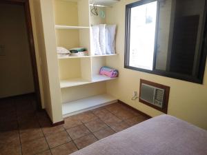 Habitación con cama, ventana y estanterías en Residencial Milton Prado en Florianópolis