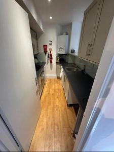 a kitchen with white cabinets and a wooden floor at Charming studio in bond street in London