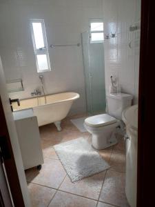 a bathroom with a tub and a toilet and a sink at Casa Fuchsia Régia em Rancho Queimado/SC in Rancho Queimado