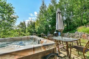 a hot tub with a table and chairs and an umbrella at Eagle's Nest in Saint-Faustin +24 photos