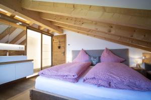ein Schlafzimmer mit einem Bett mit lila Kissen darauf in der Unterkunft Bergchalet Flöna in Scuol