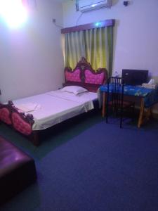 a small room with a bed and a table and a chair at Taz Garden House in Dhaka +2 photos