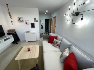 ein Wohnzimmer mit einem weißen Sofa und roten Kissen in der Unterkunft BYTEČEK U LESA in Hodonín