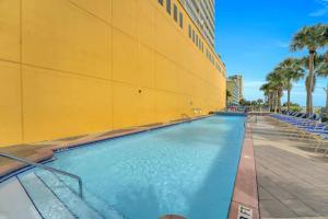 una gran piscina junto a un edificio amarillo en Sunny Shore Oasis Condo with Gulf Views, Pool and Hot Tub, en Panama City Beach