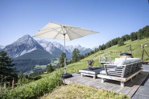eine Terrasse mit einem Sonnenschirm, einem Tisch und Stühlen in der Unterkunft Bergchalet Flöna in Scuol