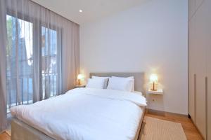 ein weißes Bett in einem Zimmer mit einem großen Fenster in der Unterkunft Teryan 54A Apartment in Yerevan