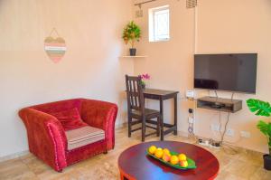 a living room with a chair a table and a tv at Fantastic location 1-Bed Apartment in Harare in Harare