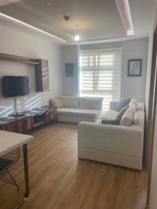 a living room with a white couch and a tv at FİNANSKENT SARPHAN RESİDANCE ATASEHİR in Istanbul