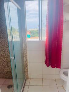 a bathroom with a shower and a toilet with a window at Mini Casa Vista Mar in Salvador