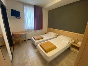 una camera d'albergo con due letti e un tavolo di Hotel Mazzini a Lido di Jesolo